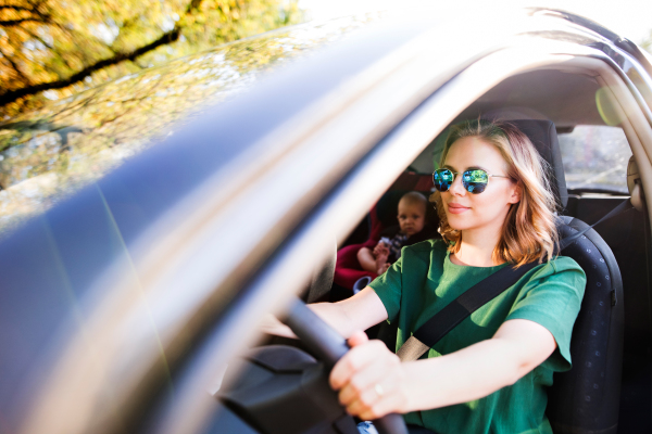 Young mother with her little son in the car. A woman driving and baby boy sitting in a car seat.