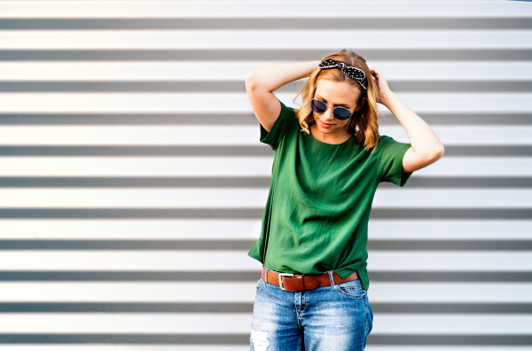 Portrait of a young woman standing against the wall.