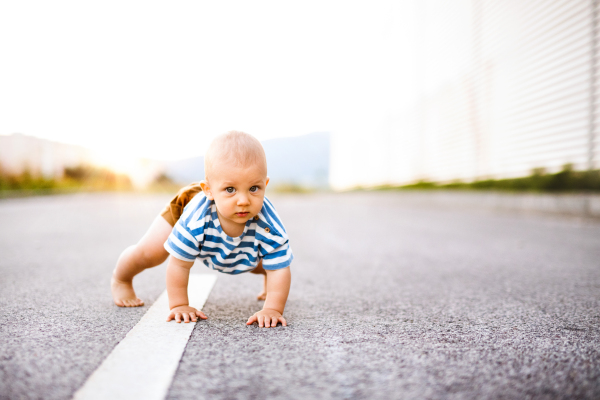 Cute little baby boy crawling outside on the road. Close up.