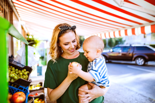 Young mother with her baby boy shopping at the outdoor market.