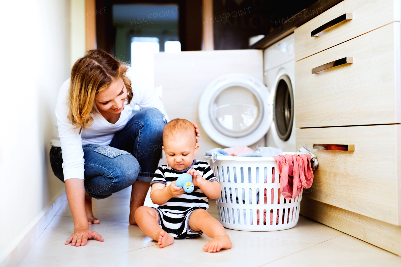 Young mother with a baby son doing housework. Beautiful woman and baby boy doing laundry.