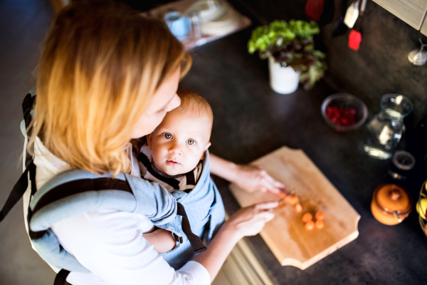 Young mother with a baby son doing housework. Beautiful woman and baby boy in the kitchen. Top view.