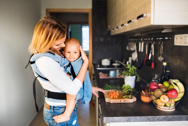 Young mother with a baby son doing housework. Beautiful woman and baby boy in the kitchen.