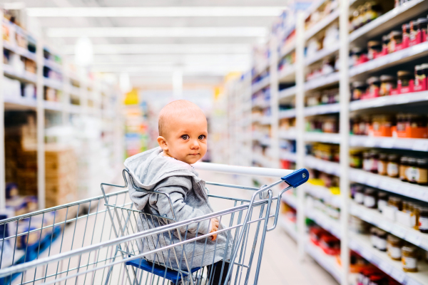 Cute little baby at the supermarket. Baby sitting in the shopping trolley.