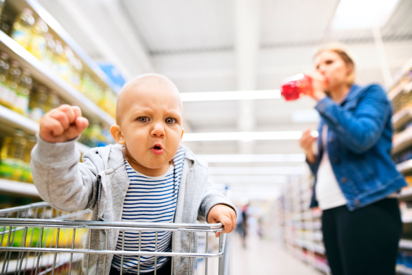 Unrecognizable young mother with her little baby boy at the supermarket, shopping.