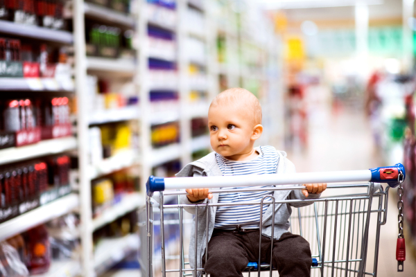 Cute little baby at the supermarket. Baby sitting in the shopping trolley.