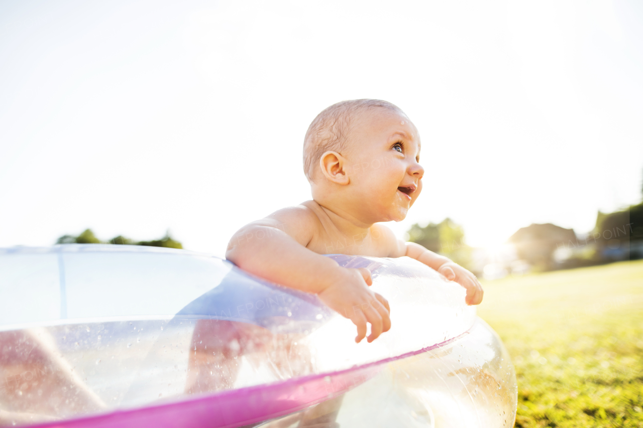 Little baby boy in the swimming pool in the garden. Summer time.