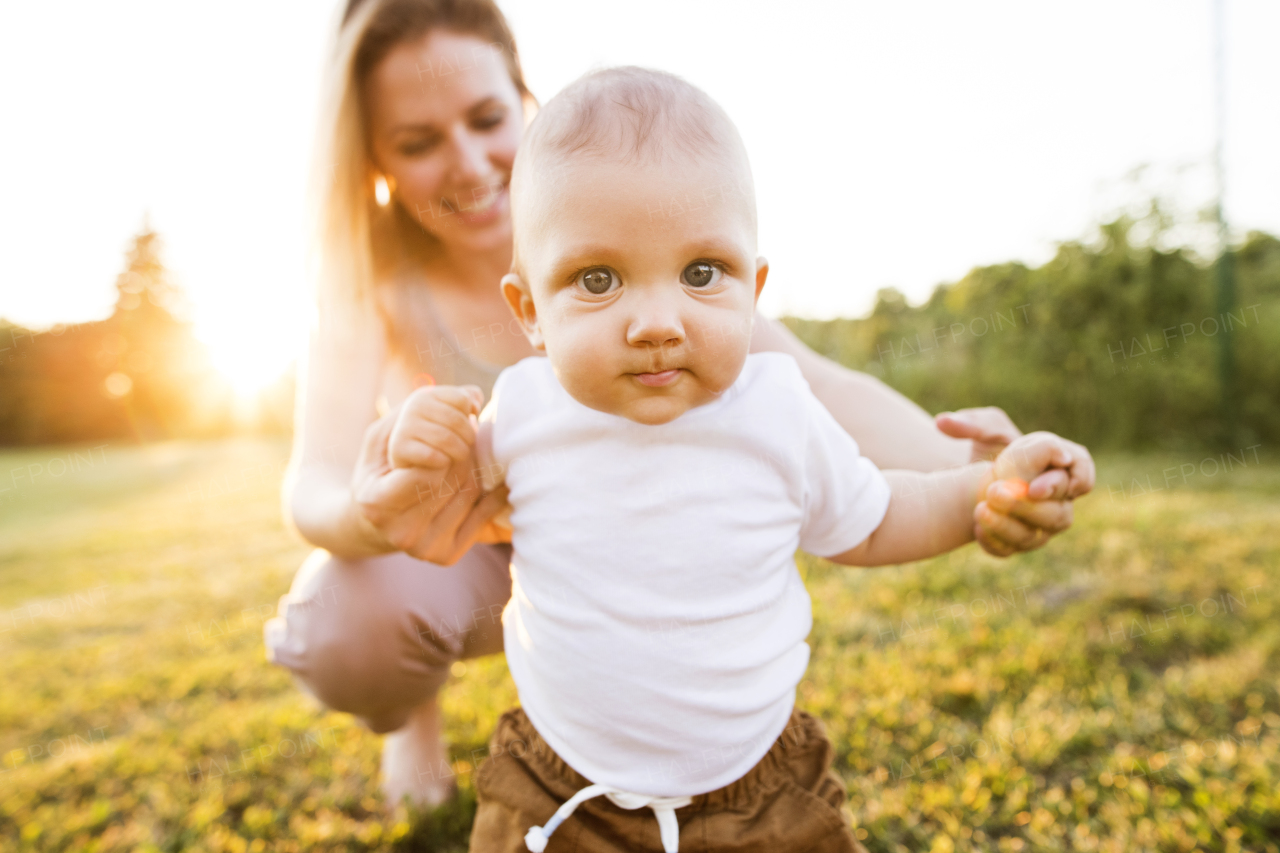 Beautiful young mother with her baby son. First steps.