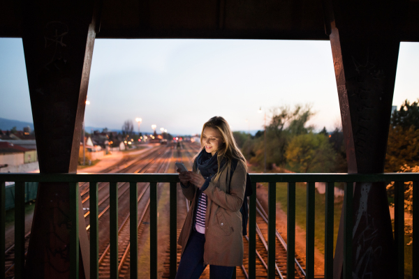 Beautiful woman in the city at night holding smartphone, texting.