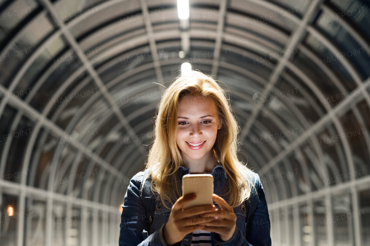 Beautiful woman in the city at night holding smartphone, texting.