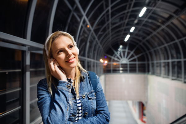 Beautiful woman in the city at night earphones on her ears, listening music.