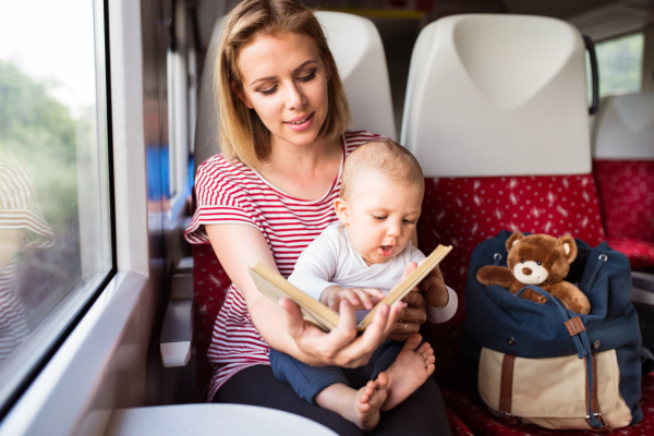 Young mother travelling with baby boy by train. Railway journey of a beautiful woman and her son.