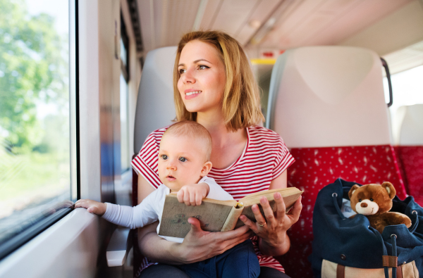 Young mother travelling with baby boy by train. Railway journey of a beautiful woman and her son.