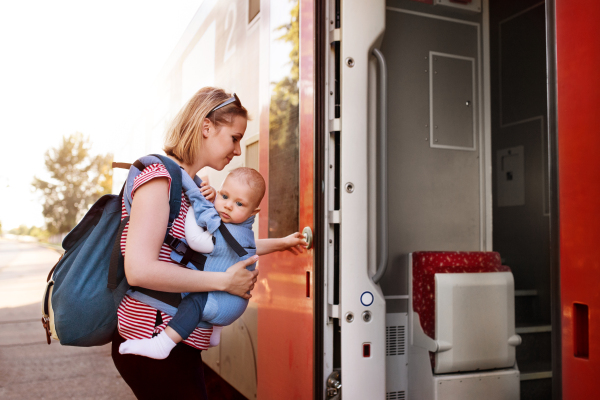 Young mother travelling with baby boy by train. Railway journey of a beautiful woman and her son.