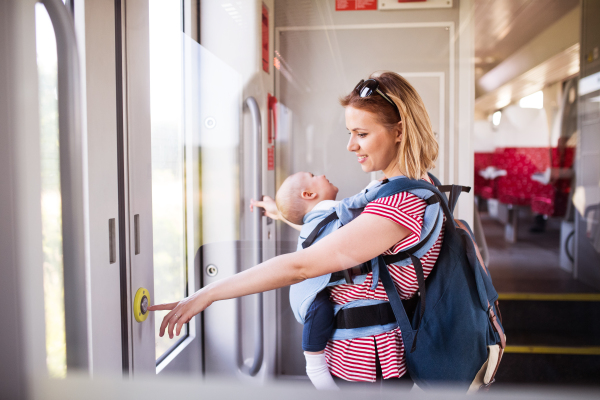 Young mother travelling with baby boy by train. Railway journey of a beautiful woman and her son.