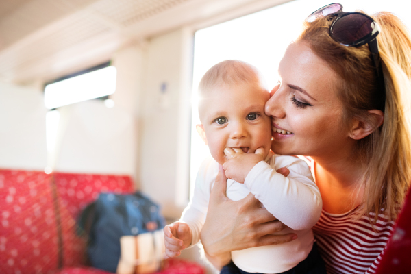 Young mother travelling with baby boy by train. Railway journey of a beautiful woman and her son.