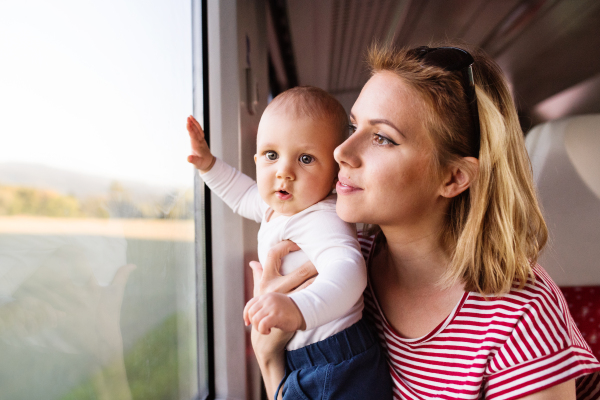 Young mother travelling with baby boy by train. Railway journey of a beautiful woman and her son.