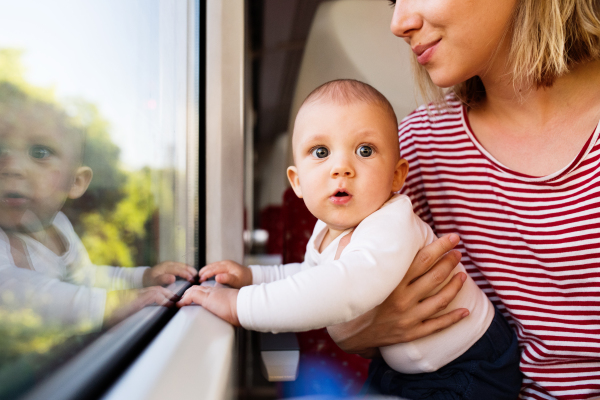 Unrecognizable young mother travelling with baby boy by train. Railway journey of a beautiful woman and her son.