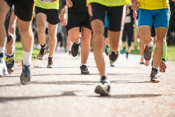 Group of unrecognizable runners sprinting outdoors. Sportive people training in a urban area, healthy lifestyle and sport concepts.