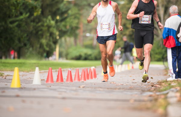 Group of unrecognizable runners sprinting outdoors. Sportive people training in a urban area, healthy lifestyle and sport concepts.