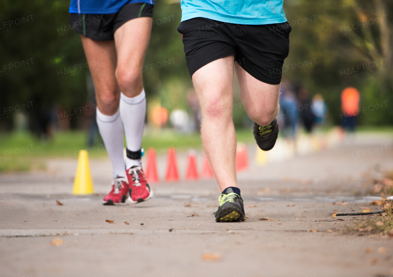 Two unrecognizable runners sprinting outdoors. Sportive people training in a urban area, healthy lifestyle and sport concepts.