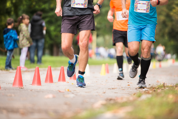 Group of unrecognizable runners sprinting outdoors. Sportive people training in a urban area, healthy lifestyle and sport concepts.