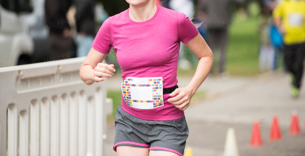 Unrecognizable young runner outdoors. Sportive woman competing in a urban area, healthy lifestyle and sport concepts.