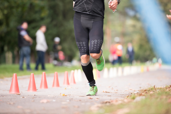 Legs of unrecognizable runner sprinting outdoors. Sportive people competing in a urban area, healthy lifestyle and sport concepts.