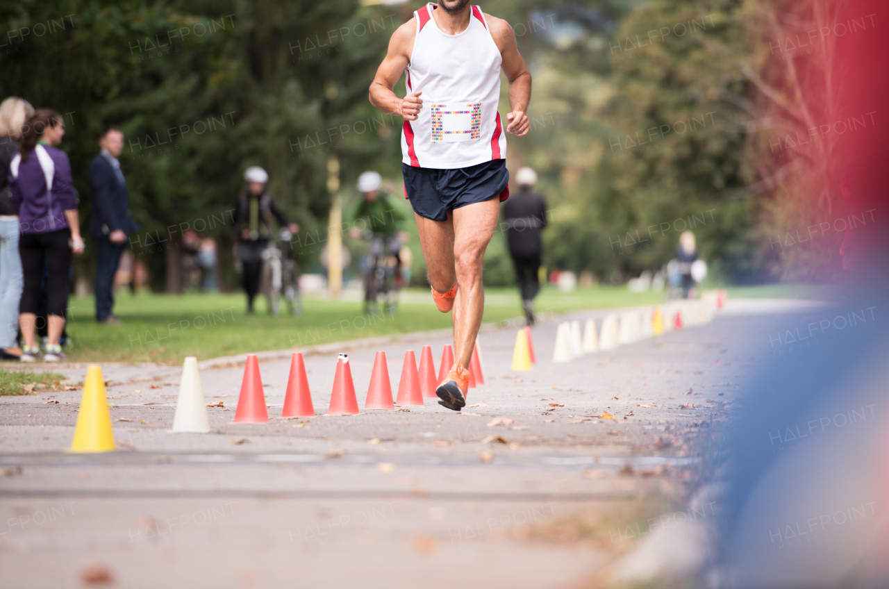 Unrecognizable runner sprinting outdoors. Sportive man competing in a urban area, healthy lifestyle and sport concepts.