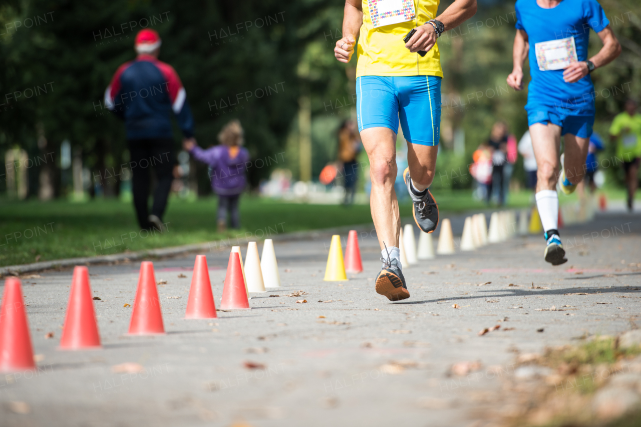 Two unrecognizable runners sprinting outdoors. Sportive people competing in a urban area, healthy lifestyle and sport concepts.