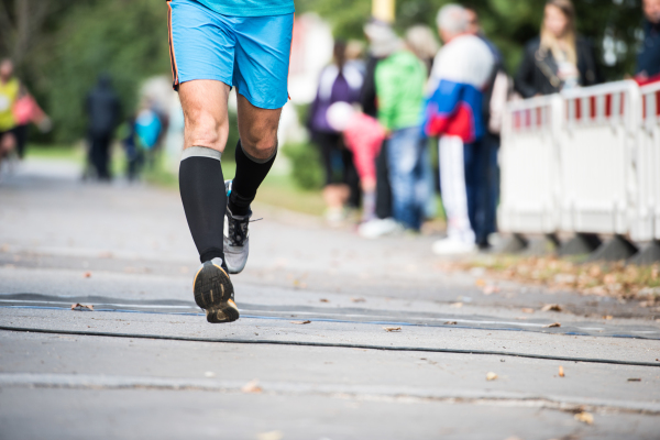 Legs of unrecognizable runner sprinting outdoors. Sportive people competing in a urban area, healthy lifestyle and sport concepts.