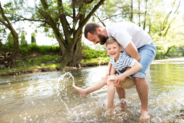 Young father with little boy in the river having fun, sunny spring day.