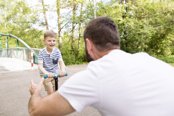 Young father with little boy outside having fun near river, sunny spring day.