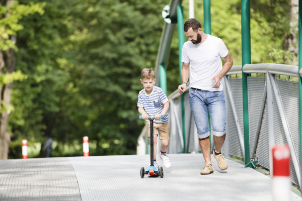 Young father with little boy outside having fun near river, sunny spring day.