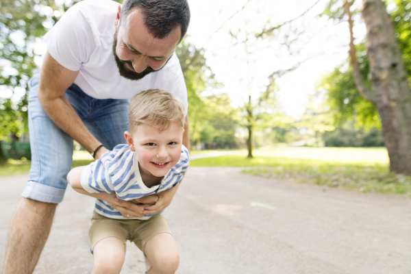 Young father with little boy outside having fun, sunny spring day.