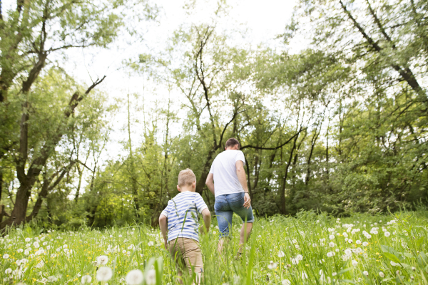 Young father with little boy outside having fun, sunny spring day.