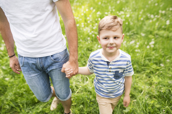 Young father with little boy outside having fun, sunny spring day.