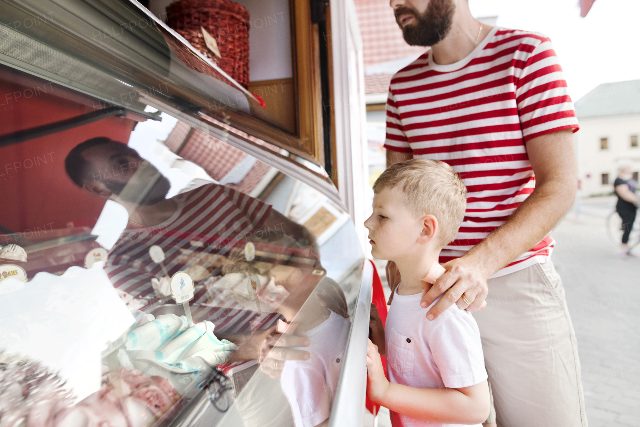 Young father and his little son buying ice cream. Sunny summer day.