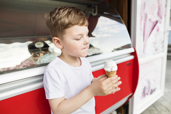 Cute little boy eating ice cream. Sunny summer day.