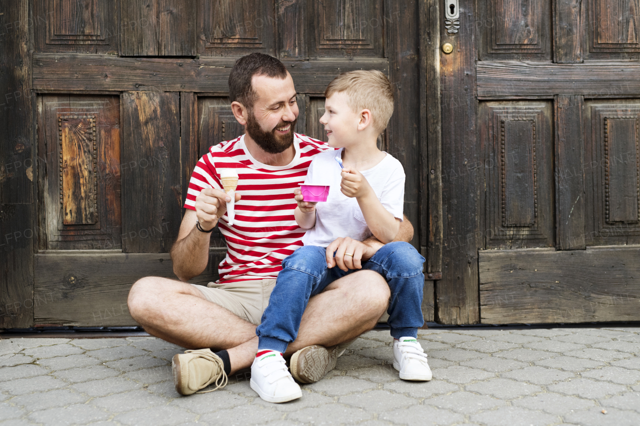 Young father and his little son eating ice cream. Sunny summer day.