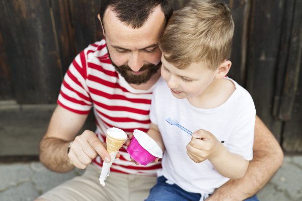 Young father and his little son eating ice cream. Sunny summer day.