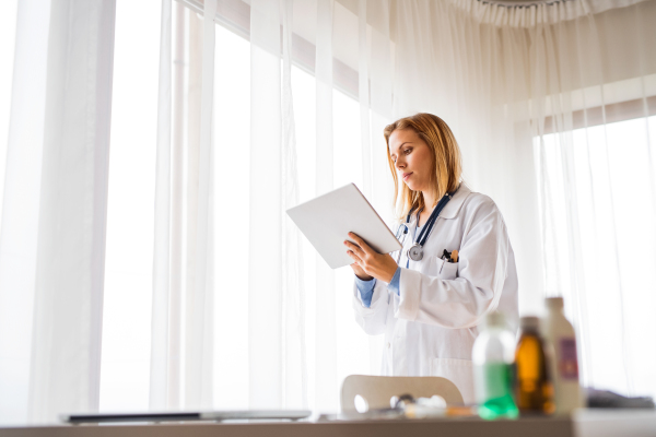 Young female doctor with tablet working at the office.