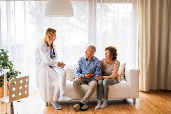 Young female doctor talking to a senior couple. Home visit.