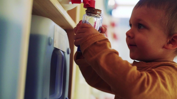 A close-up of cute small toddler boy standing by dispensers in zero waste shop. Slow motion.