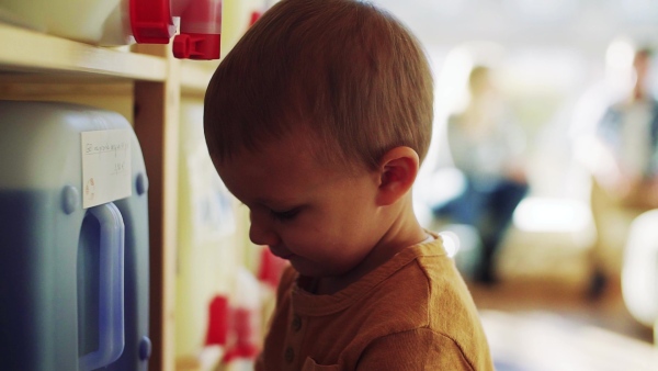 A cute small toddler boy standing by dispensers in zero waste shop. Slow motion.