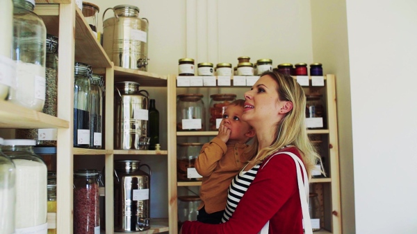 An attractive young woman with a toddler boy buying groceries in zero waste shop. Slow motion.