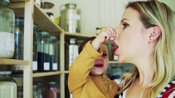 An attractive young woman standing with a toddler boy in zero waste shop, playing when buying groceries. Slow motion.