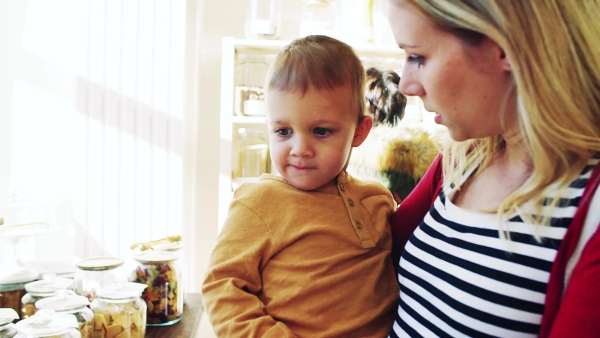 An attractive young woman with a toddler boy buying groceries in zero waste shop. Slow motion.