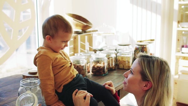 An attractive young woman with a toddler boy buying groceries in zero waste shop. Slow motion.