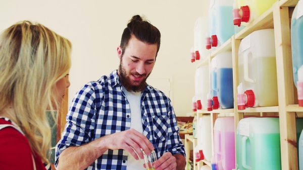 Young male shop assistant serving an attractive woman in a zero waste shop. Slow motion.